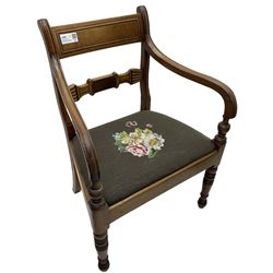 Regency mahogany elbow chair, carved shaped central back bar, over drop-in seat upholstered in floral needlework, raised on ring turned front supports