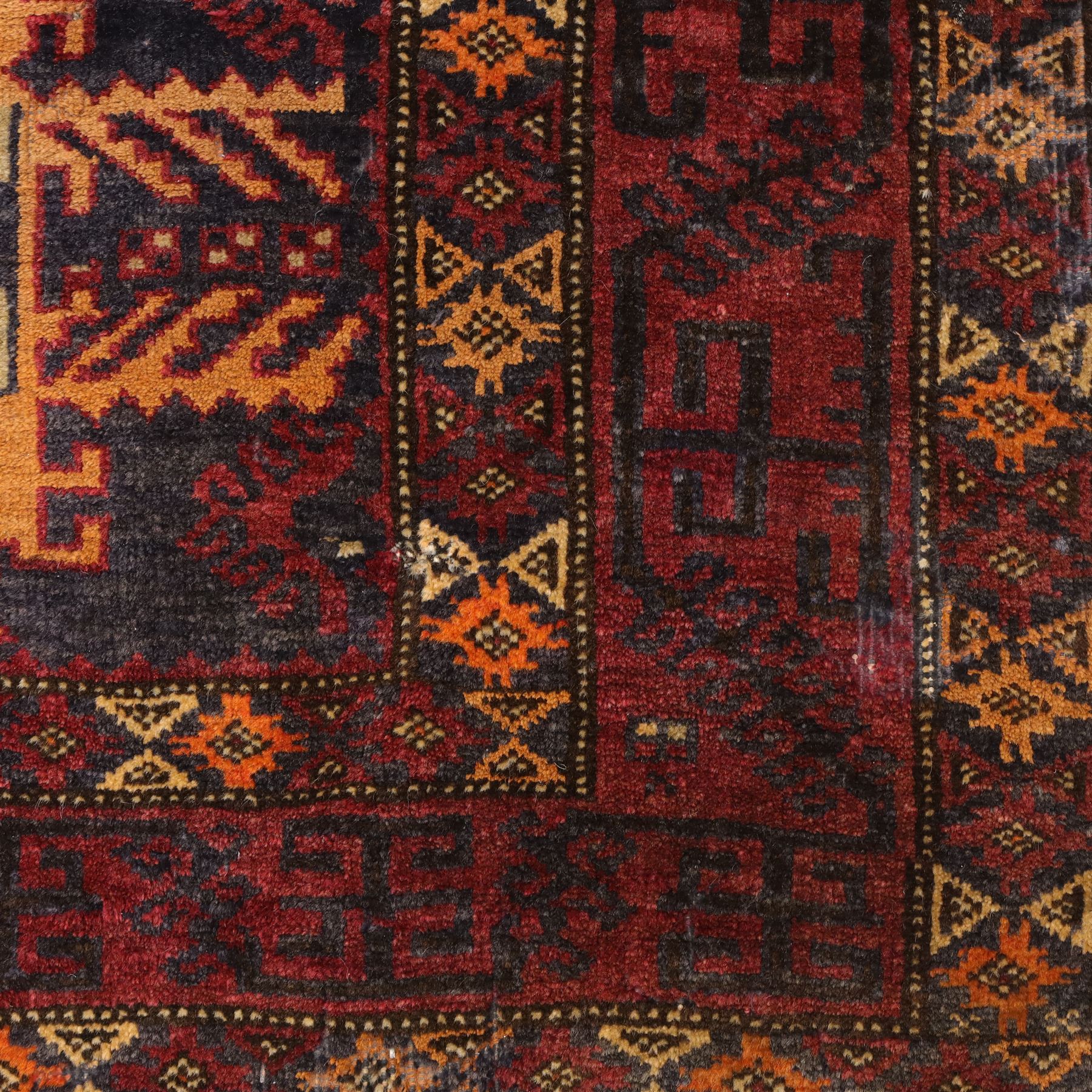 Baluch hand-knotted rug, deep red and indigo field decorated with a vertical arrangement of stylized geometric medallions within multiple narrow borders, 95x163cm, and Tekke Turkman rug, madder red field decorated with repeating rows of octagonal guls, framed by multiple geometric borders 84x129cm, (2)