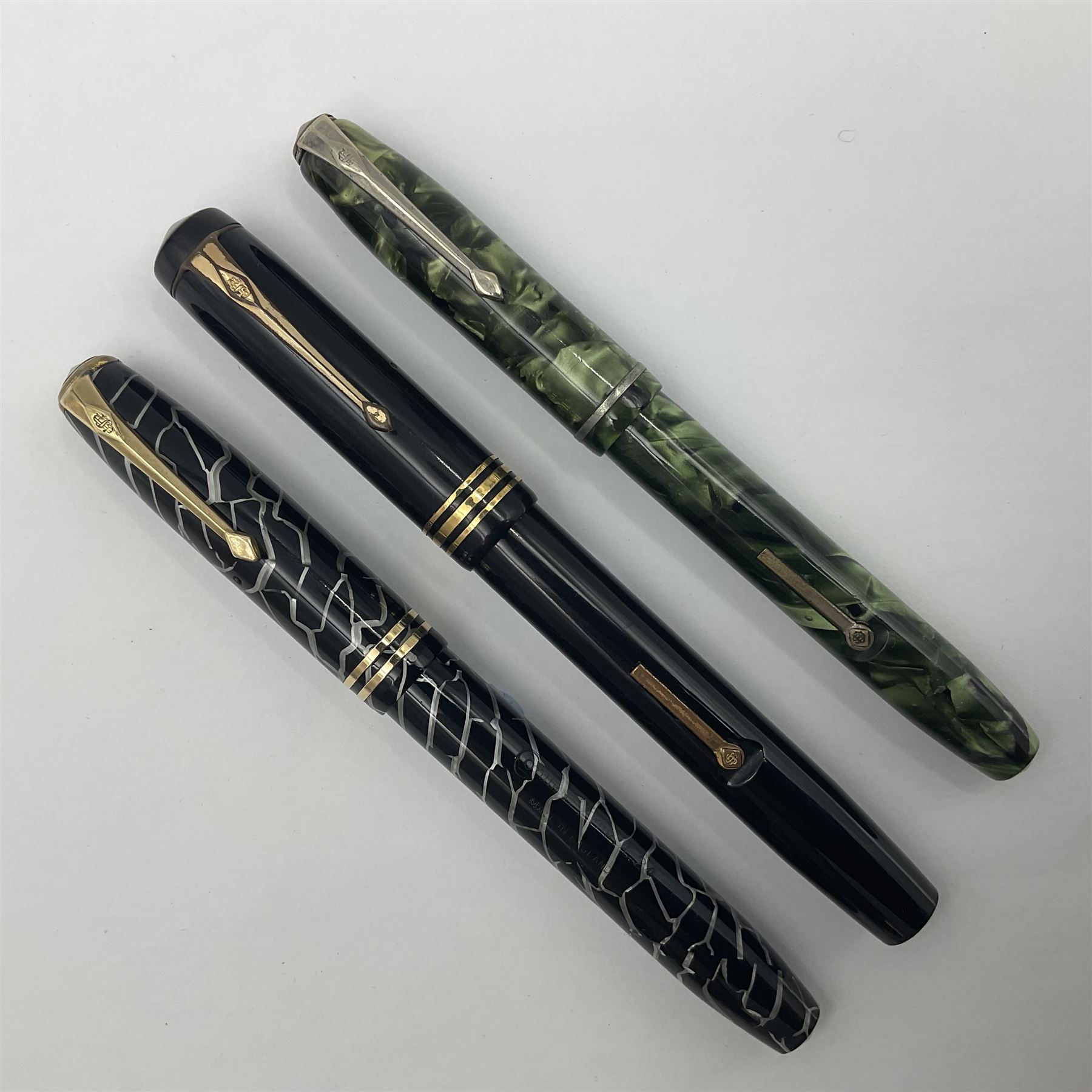 Three Conway Stewart fountain pens, comprising Cracked Ice 28 pen, the black and pearl white barrel engraved Conway Stewart 28 and double banded cap, with gold nib stamped 14ct, together with a Conway Stewart 75 lever fill pen, the green marble barrel and cap with single band and gold nib stamped 14ct and Conway Stewart 55 lever fill fountain pen with black barrel and cap with single broad band and two narrow bands with gold nib stamped Duro 14ct, largest L13cm