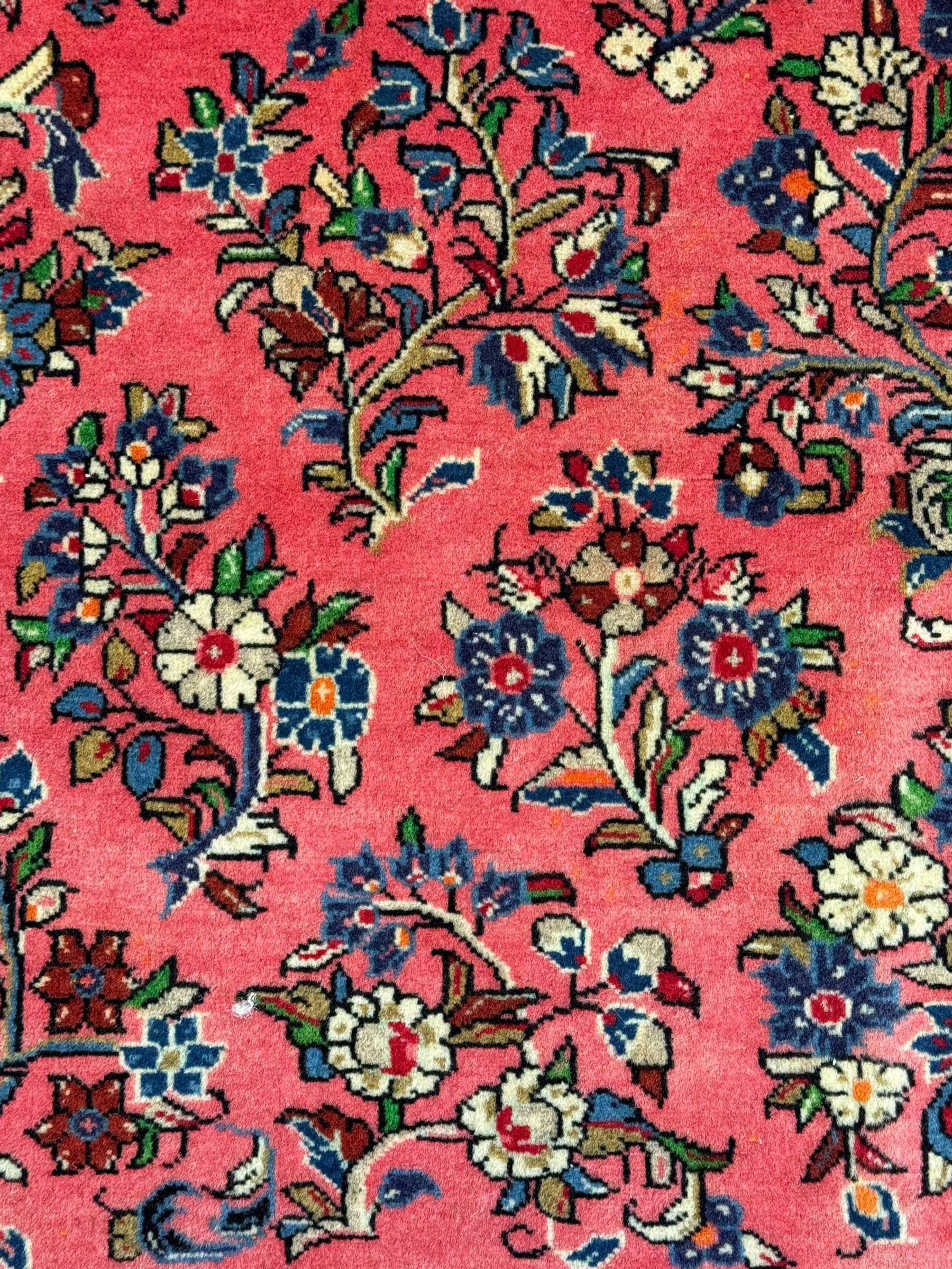 North West Persian Sarouk peach ground rug, the field decorated with floral bunches, pale ground border with repeating flower head motifs within guard stripes 