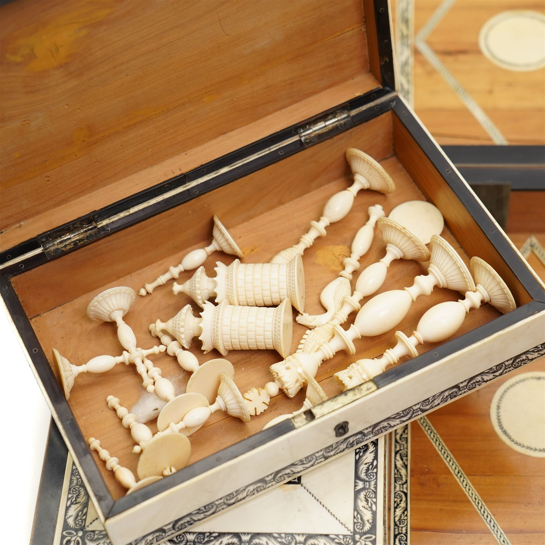 Mid-19th-century Anglo Indian Vizagapatam ivory, sandlewood, and horn veneered backgammon/chess board, circa 1860, rectangular games box the borders engraved with a stylized scrolling leaf decoration and spine engraved History of Persia the interior inlaid for backgammon, with three internal sandalwood boxes with covers, containing 16 ivory pieces and 16 horn pieces, comprising, kings and queens with pierced crowns on baluster carved shafts; bishops with carved mitres; knights represented by horses’ heads; and rooks as towers with imbricated decoration.

This item has been registered for sale under section 10 of the APHA Ivory Act, submission reference G68PNYA5 

