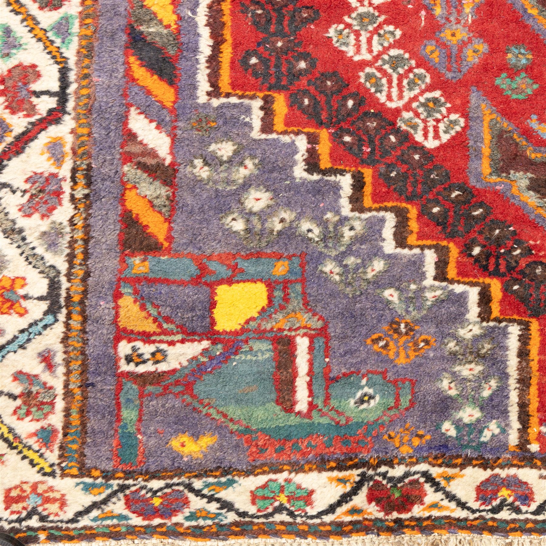 Northwestern Persian village rug, madder red field, with serrated central panel enclosing three linked lozenge medallions, polychromed spandrels, ivory border, and geometric guard stripes  