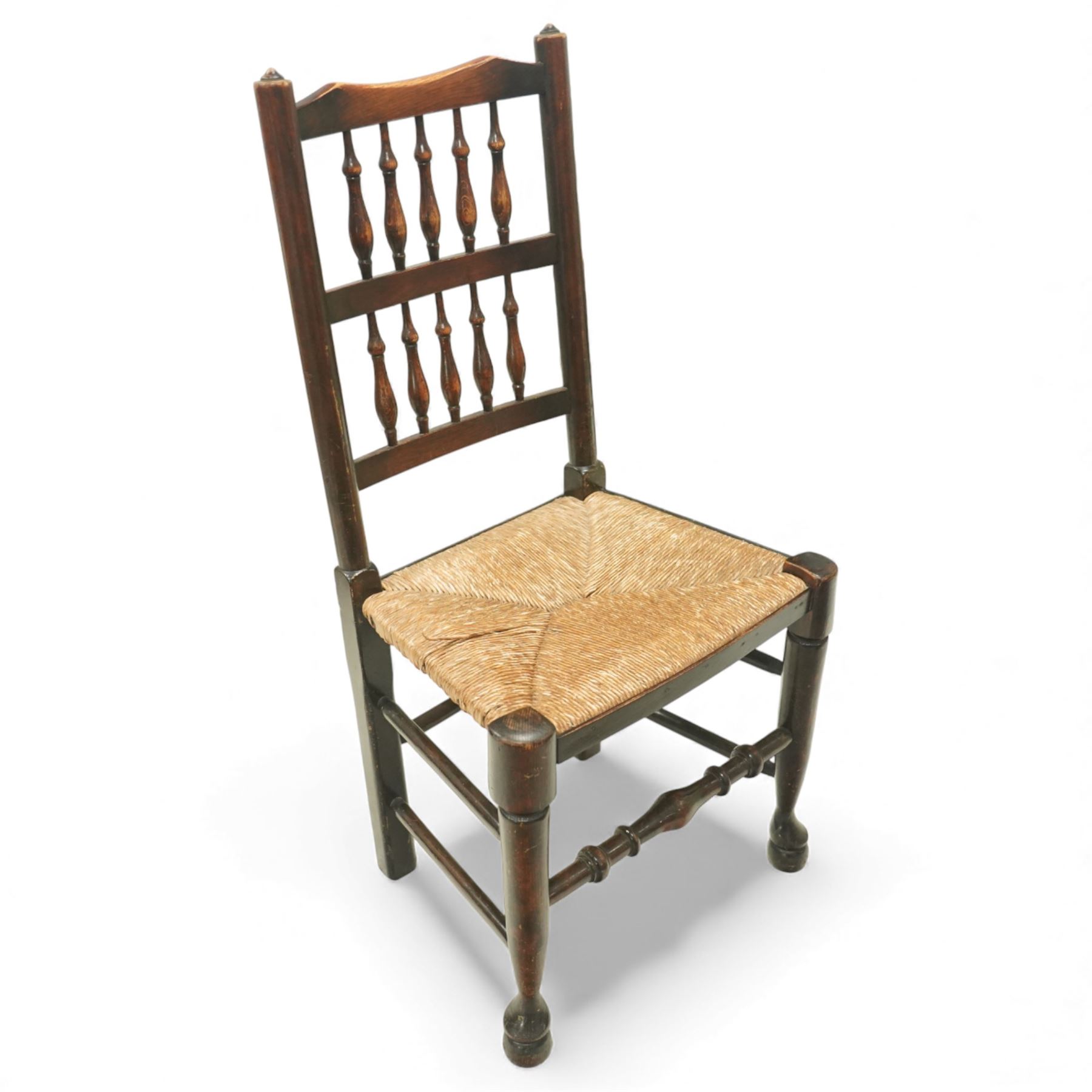 20th century set of five spindle-back dining chairs, with shaped top rails above turned spindle splats, rush seats, turned forelegs united by stretchers
