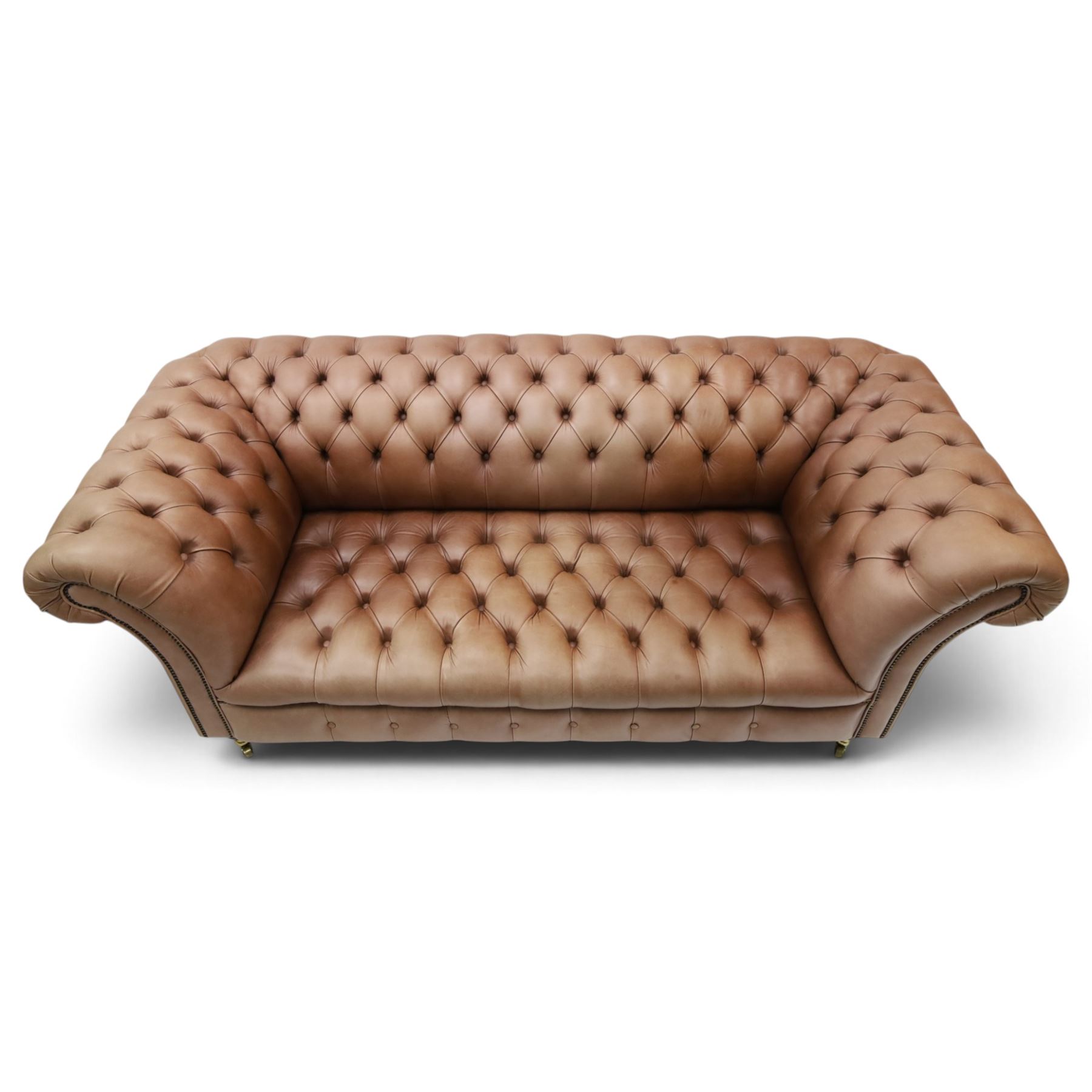 Distinctive Chesterfield - full buttoned tan brown leather sofa, deep buttoned back, seat and arms, raised on dark stained supports terminating in brass castors 