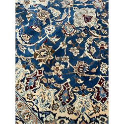 Persian Kashan blue ground rug, central floral rosette medallion within a field of swirling branches and palmettes, the border with trailing pattern interspersed with stylised plant motifs