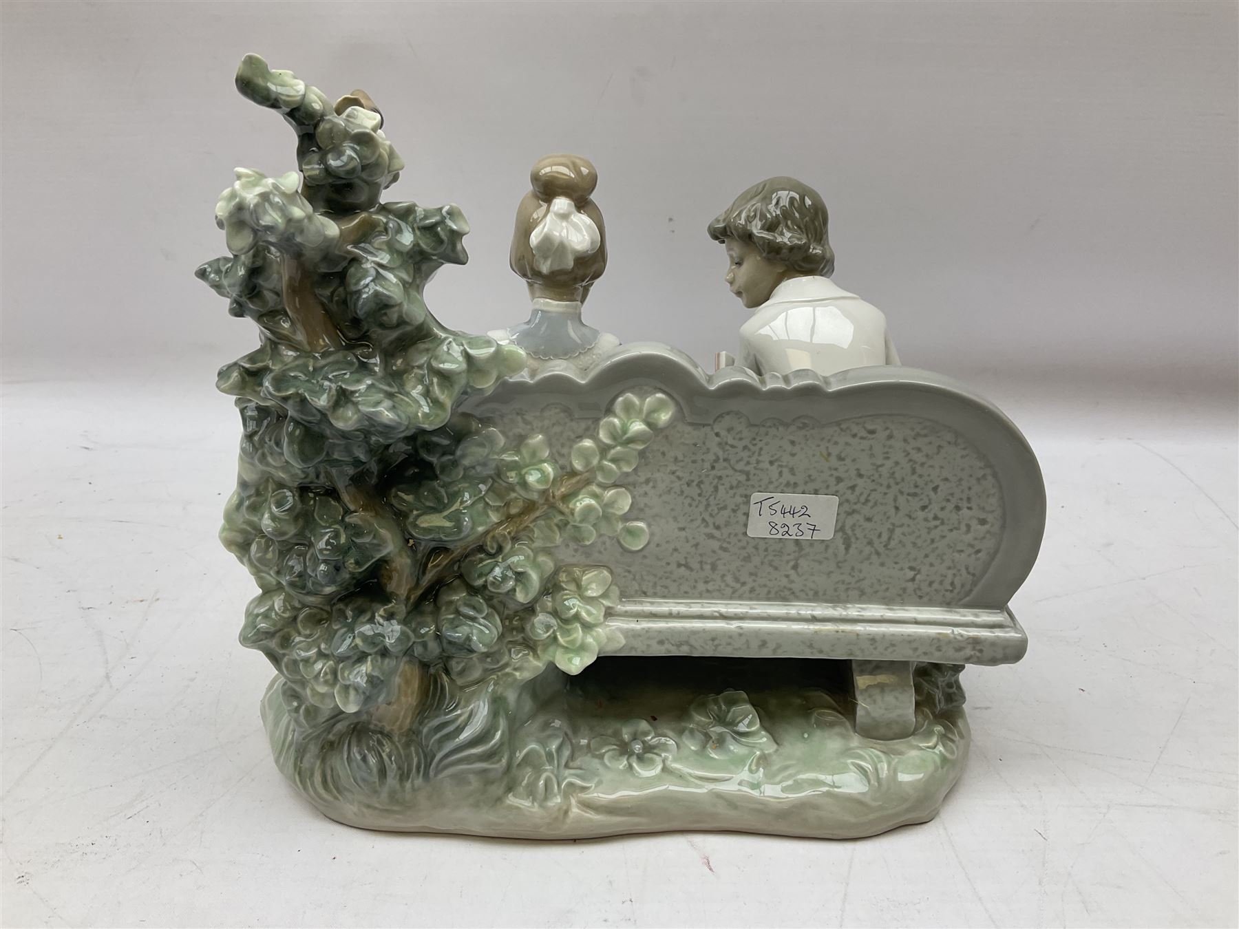 Lladro figure, Poetry of Love, modelled as a boy seated reading from a book next to a girl on garden bench with a dog at her feet, sculpted by Regino Torrijos, with original box, no 5442, year issued 1987, year retired 1998, H22cm