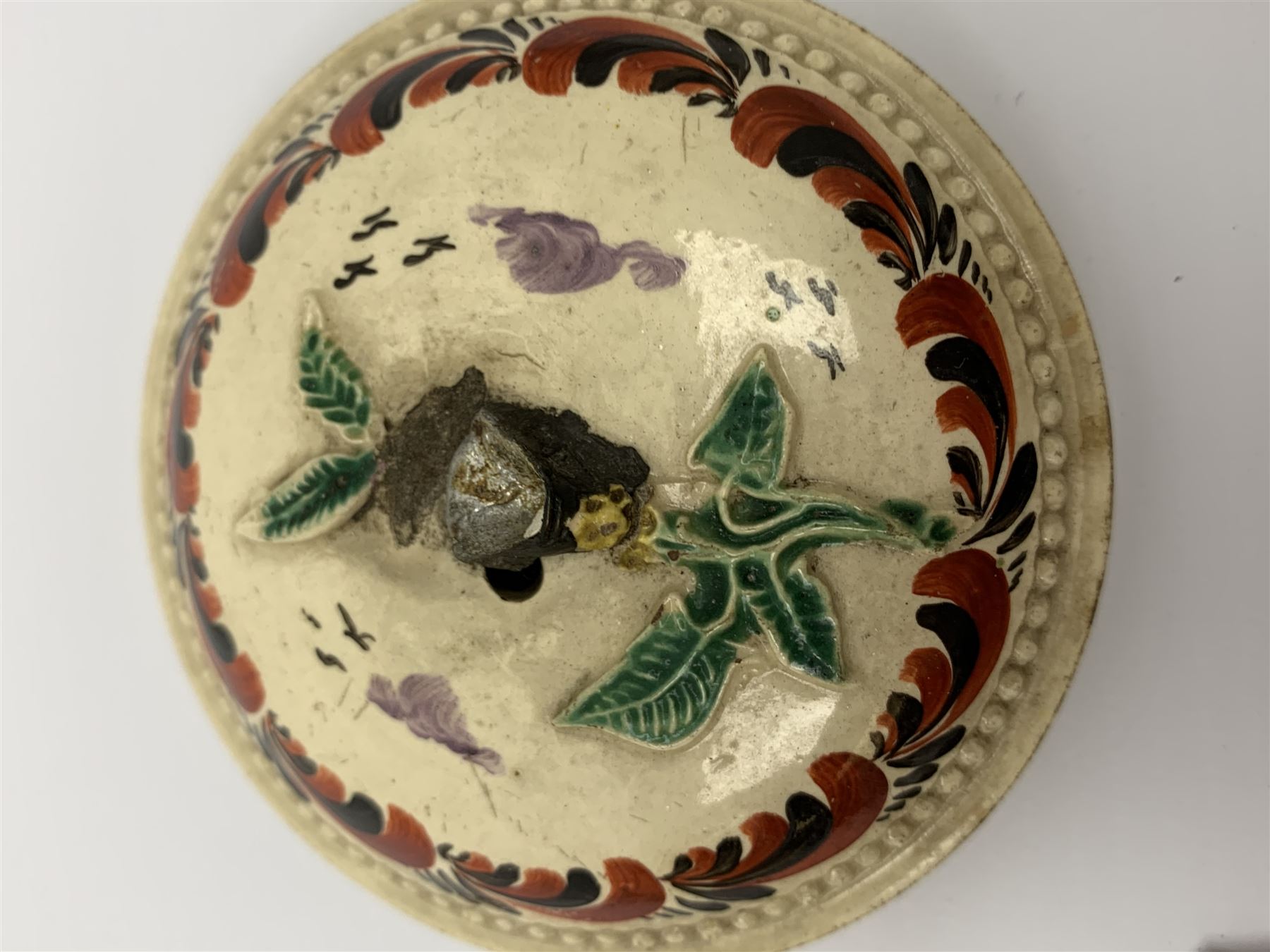 18th century creamware teapot, probably Leeds, with reeded entwined handle and floral finial to the cover, the body with hand painted polychrome decoration of figure to one side, and floral spray to the other, collectors paper label beneath inscribed Leeds Pottery, H11.5cm