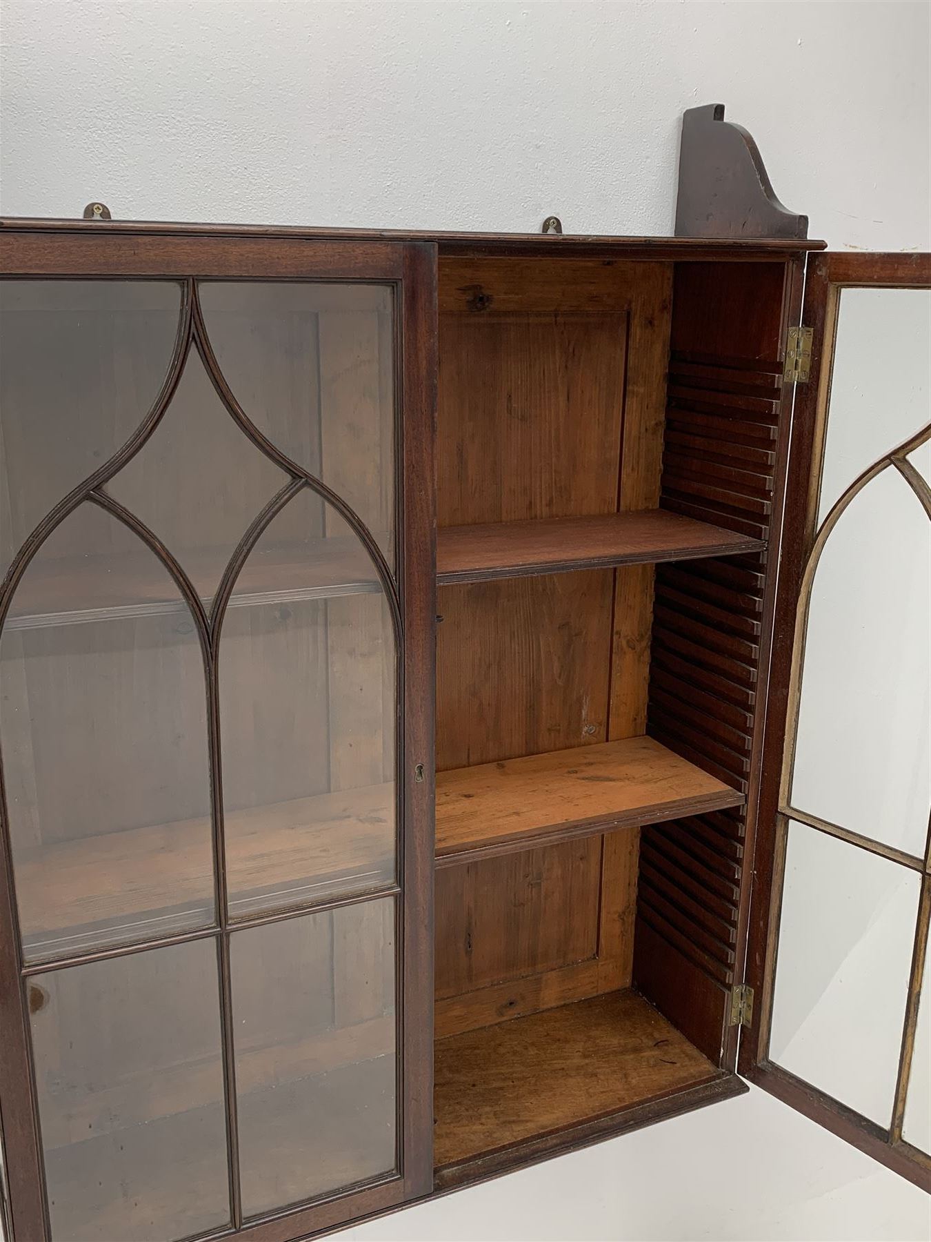 Georgian mahogany Gothic wall hanging cabinet, enclosed by two ogee pointed arch astragal glazed doors, plain sides with shaped top and bottom brackets