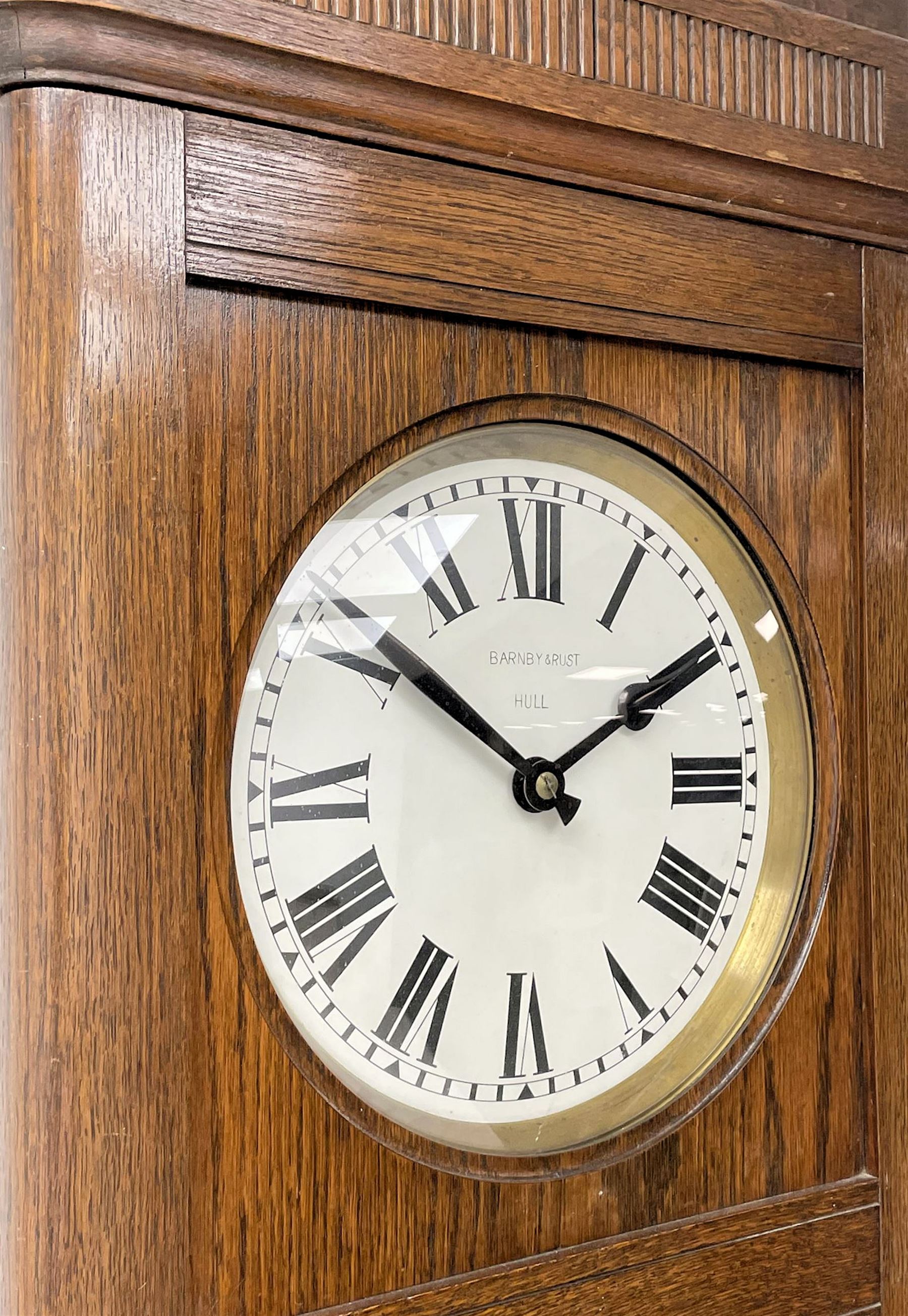Early 20th century Art Deco oak longcase clock, circular dial with roman numerals and minute track, dial signed 'Barnby & Rust, Hull', twin chain driven movement striking the hours on gong rods. With weights and Pendulum.