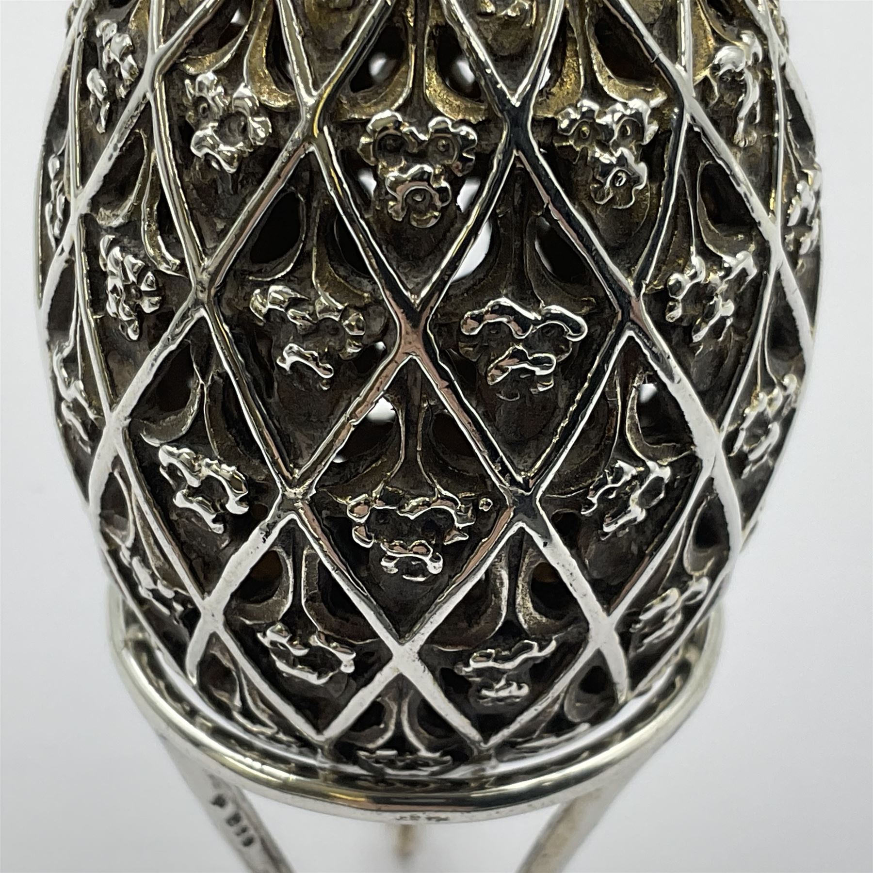 Modern silver limited edition Easter egg, no. 70/500, the openwork lattice body decorated with gilded panels of flower heads, opening to reveal a gilt interior, upon silver stand with three scrolling pad feet, each hallmarked St James House Company, London 1979, height including stand 8cm