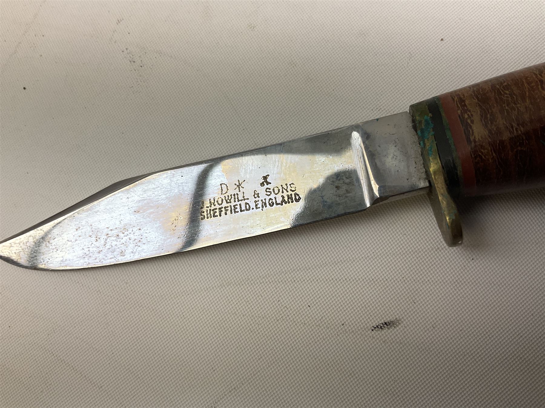 Graduated set of three Bowie knives by J. Nowill & Sons Sheffield England Est. AD1700, each with steel blade, brass cross-piece, stacked leather type grip and alloy pommel; largest blade 13cm and smallest 7.5cm; each in leather sheath (3)