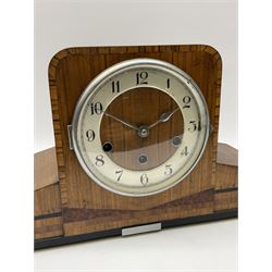 A 1930’s eight-day three train art deco Westminster chiming mantle clock with a Haller & Benzing (German) movement chiming the quarters on five underslung gong rods, silver effect chapter ring with upright Arabic numerals and minute track, strike/silent lever, chrome spun bezel with a convex glass, pierced chrome hands, walnut veneered case inlaid with cross banding and inlaid with amboyna and ebony.
With pendulum.
Haller & Benzing were a short-lived firm of German clockmakers with a factory in Villingen-Schwenningen from 1918 to 1929, mainly known for producing industrial clocks, their domestic clocks are not as well known. 
