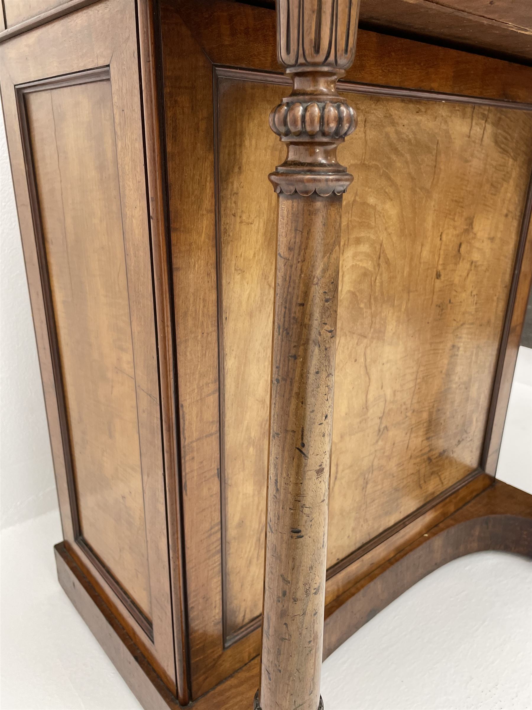 Early Victorian figured mahogany dressing cabinet, the raised shell and scroll carved back lifts to reveal rectangular easel mirror with mahogany band, flat rectangular top with tooled leather inset, slide at each side with matching leather inset, full width drawer above cupboard enclosing a series of five drawers, turned front supports, panelled front, sides and back