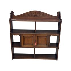 20th century carved mahogany hanging wall shelf, shaped top rail with carved fan motif over central twin cupboard flanked by fixed shelves, open base with three-tier shelving