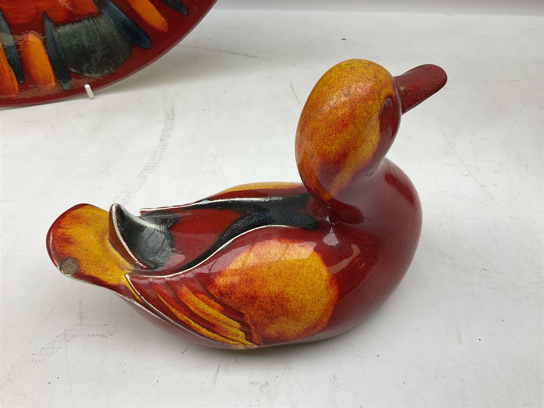 Collection of Poole Pottery, comprising charger and vase in Volcano pattern and a duck figure in a similar pattern 