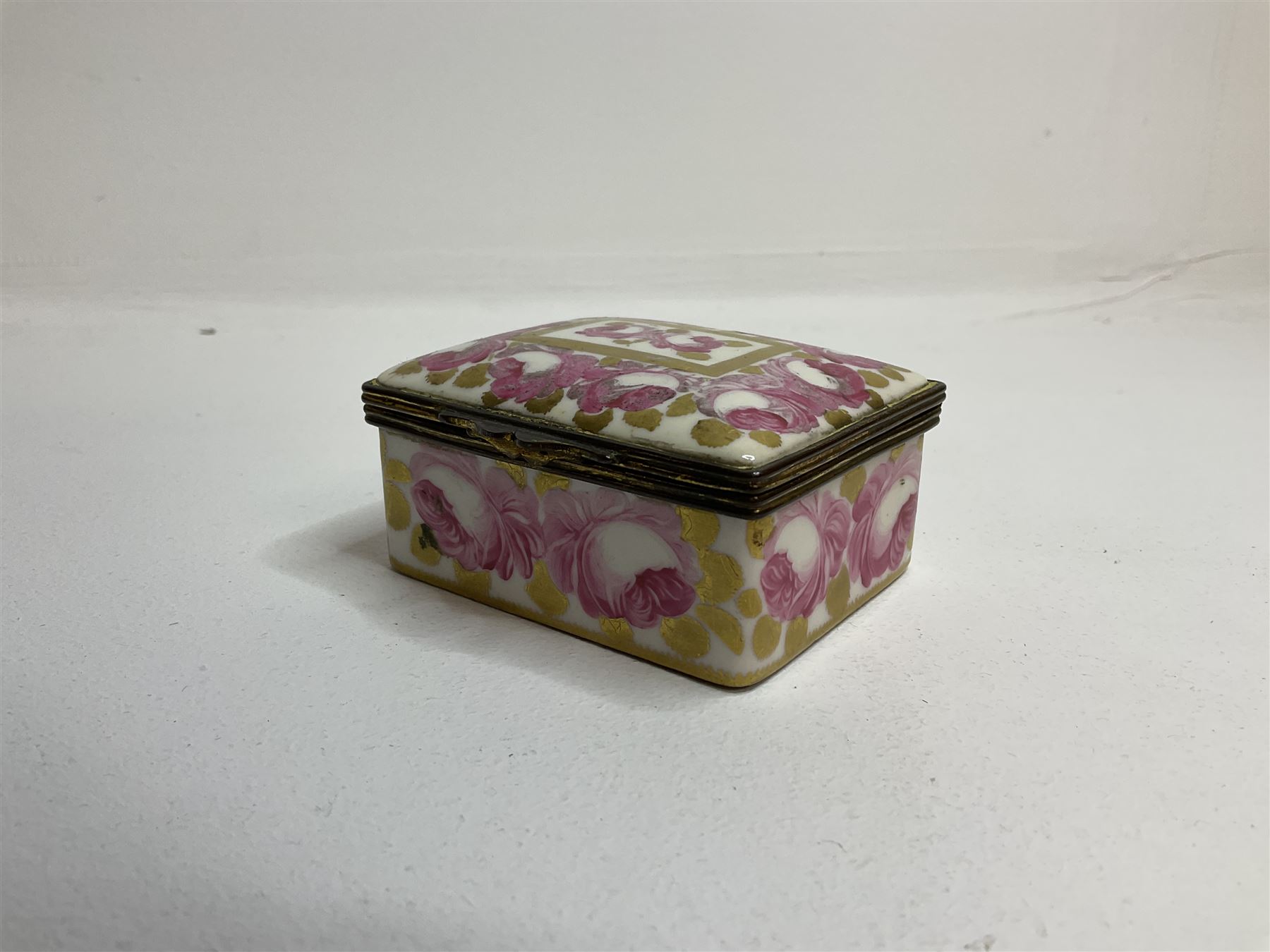 Early 19th century Swansea box of rectangular form, densely decorated with painted pink cabbage roses and gilt foliage upon plain ground, the hinged lid opening to reveal interior painted with two further roses upon plain ground, marked Swansea. in gilded lettering beneath, W7cm H3.5cm D5.5cm