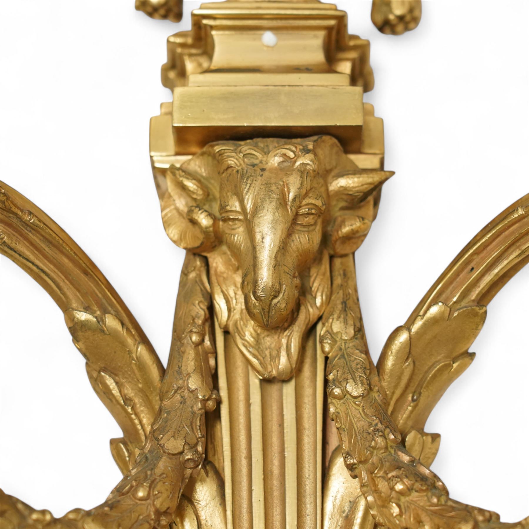 Pair of 19th-century Louis XVI-style ormolu rams-headed two-light wall appliques, the arms joined by a garland of laurel leaves, the half fluted stem surmounted by a vase with laurel garland, wired for electricity 