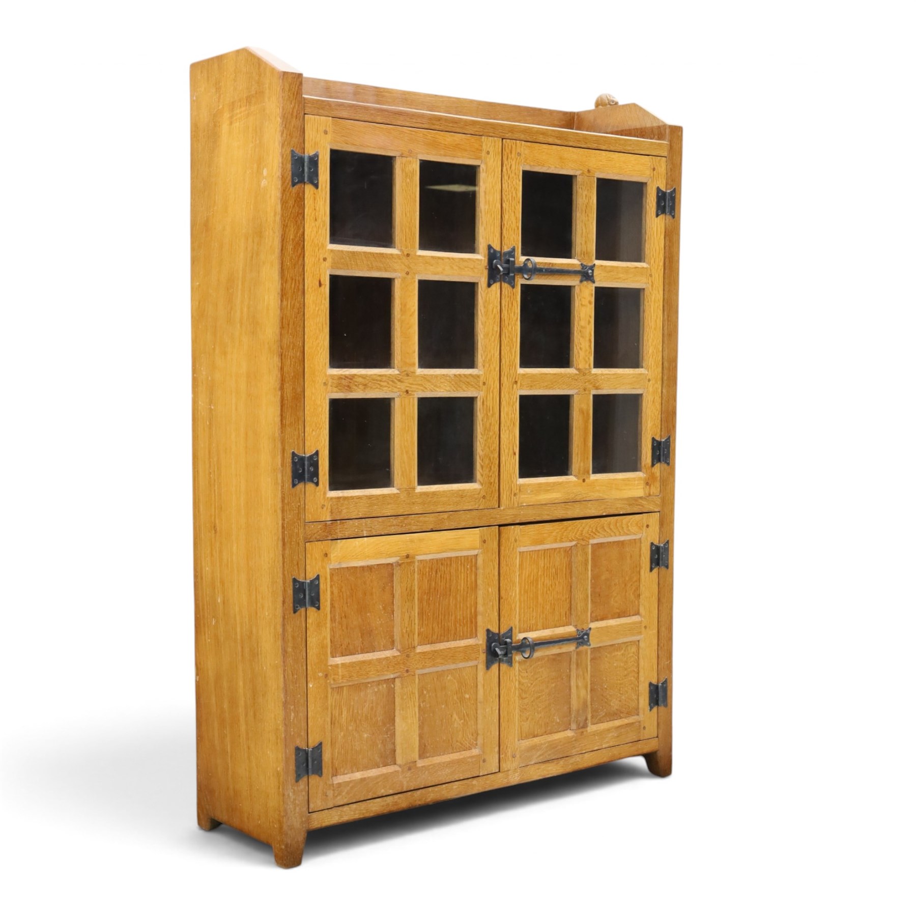 Rabbitman - oak glazed bookcase or display cabinet, lightly adzed rectangular top with raised gallery, twin glazed doors enclosing two shelves, over a pair of panelled cabinet doors with wrought iron fittings, with carved rabbit signature, by Peter Heap of Wetwang