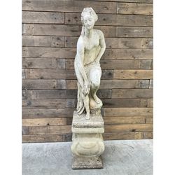 Cast stone garden statue of partially draped classical female figure on ornate pedestal 