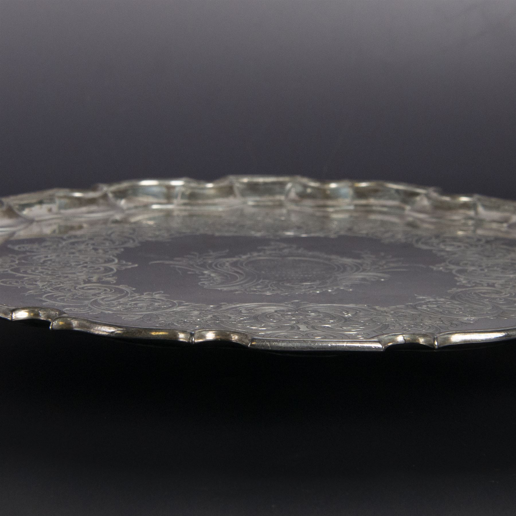 George II silver salver, of circular form with pie crust rim, with later floral and foliate decoration and presentation engraving to centre, upon three stepped feet, hallmarked William Peaston, London 1749, D30cm