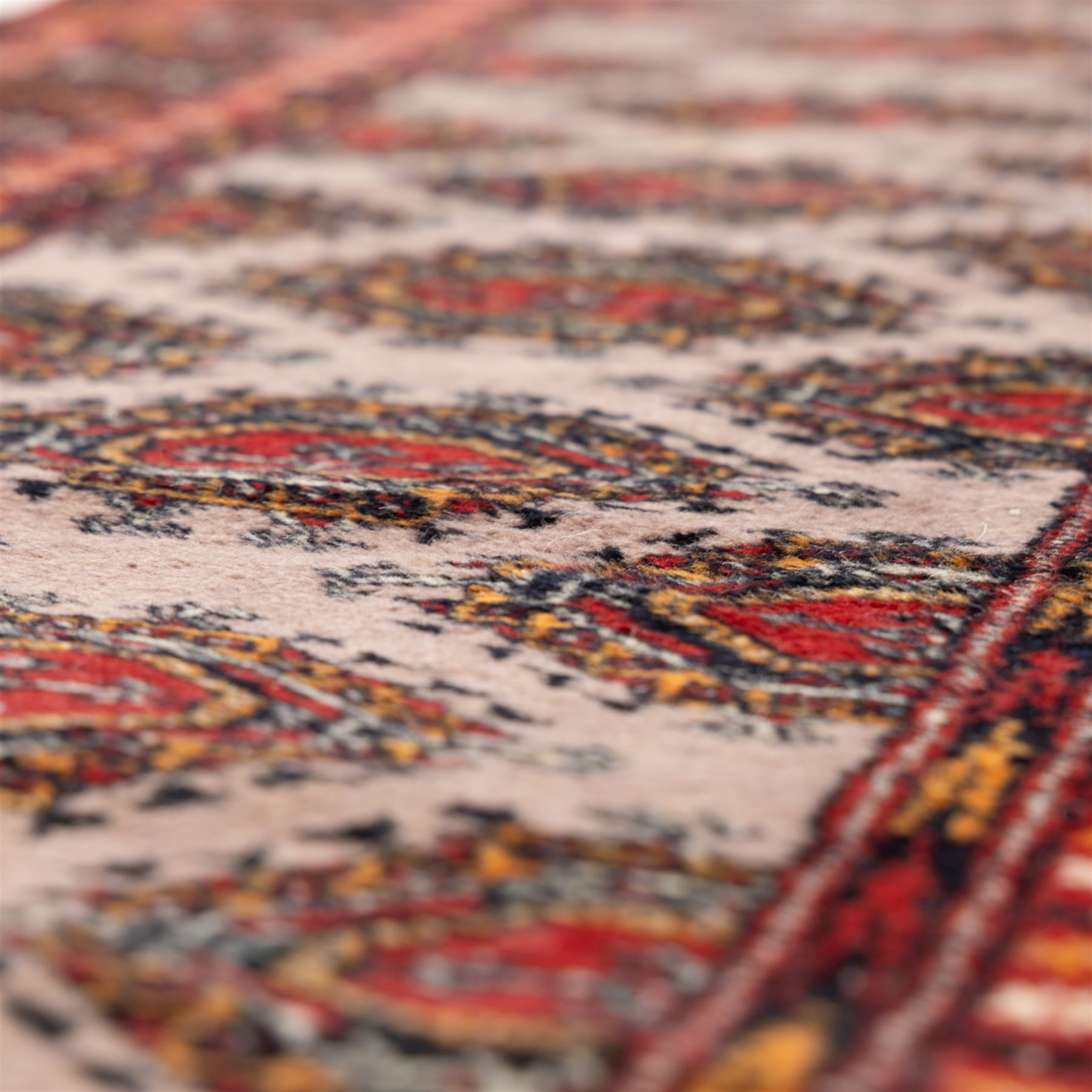 Tekke Bokhara hand knotted  runner, crimson field decorated with a series of repeating Tekke gul motifs arranged in rows within narrow geometric borders with chevron and diamond devices, 78x248cm 