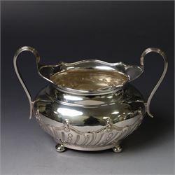 Edwardian silver three piece tea service, comprising teapot, twin handled open sucrier and a cream jug, each of oval form with embossed scrolling decoration and upon four bun feet, the teapot with ebonised wooden handle and finial, hallmarked Thomas Bradbury & Sons Ltd, Sheffield 1903, teapot H16cm