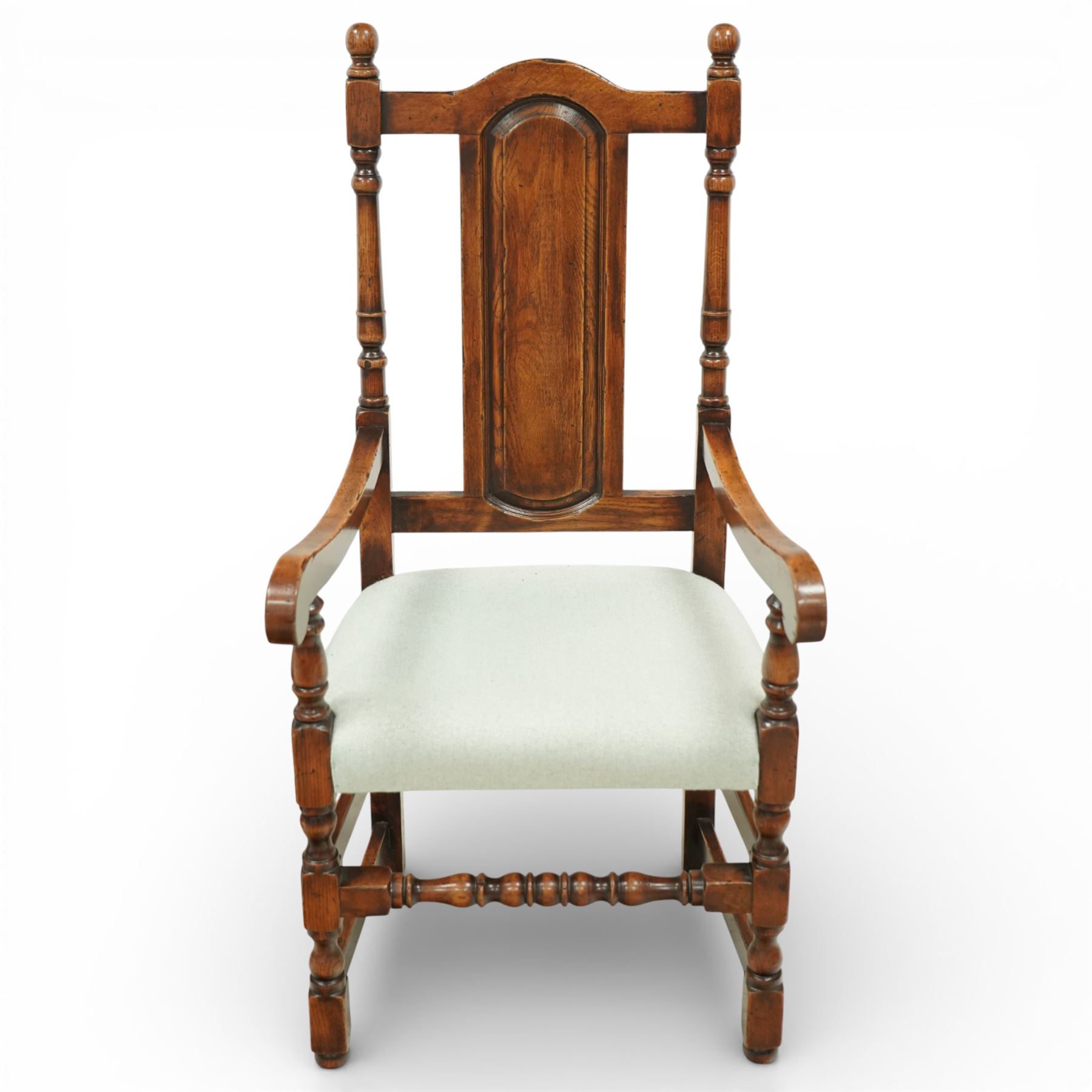 Country House oak high back dining chairs, set of ten comprising eight side chairs and two carvers, each with arched top rail flanked by turned finials over a central fielded panel back, with overstuffed seats upholstered in pale fabric, raised on turned front supports united by stretchers