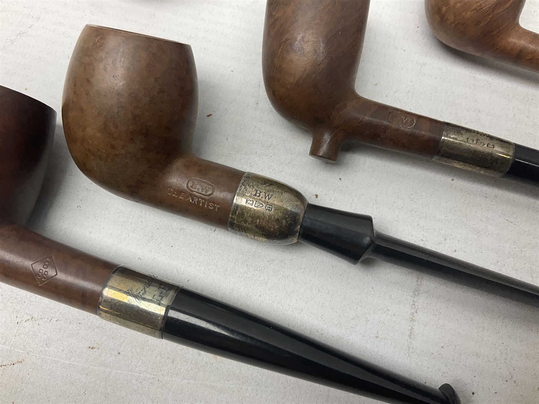 Collection of eight silver mounted pipes, comprising a briar wood Imperial ITC example with silver collar hallmarked A.W Birmingham 1903, horn handled example with silver collar hallmarked LB, probably Louis Blumfeld, Birmingham 1900, three examples marked B.W, one marked Globe A.O.C, Blumfeld's Best Briar pipe marked BBB and Riseagle example, together with two further pipes (10)