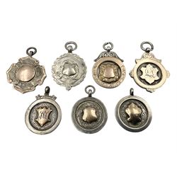 Seven early 20th century silver gold faced cartouche fobs, to include a circular example, with rose gold border and cartouche within an embossed yellow gold border, engraved verso, and a double sided example, all hallmarked with various dates and makers

