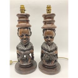Pair of 20th century carved wood table lamp with African busts and figures, together with a carved wooden figure and soapstone figure, lamps H44cm