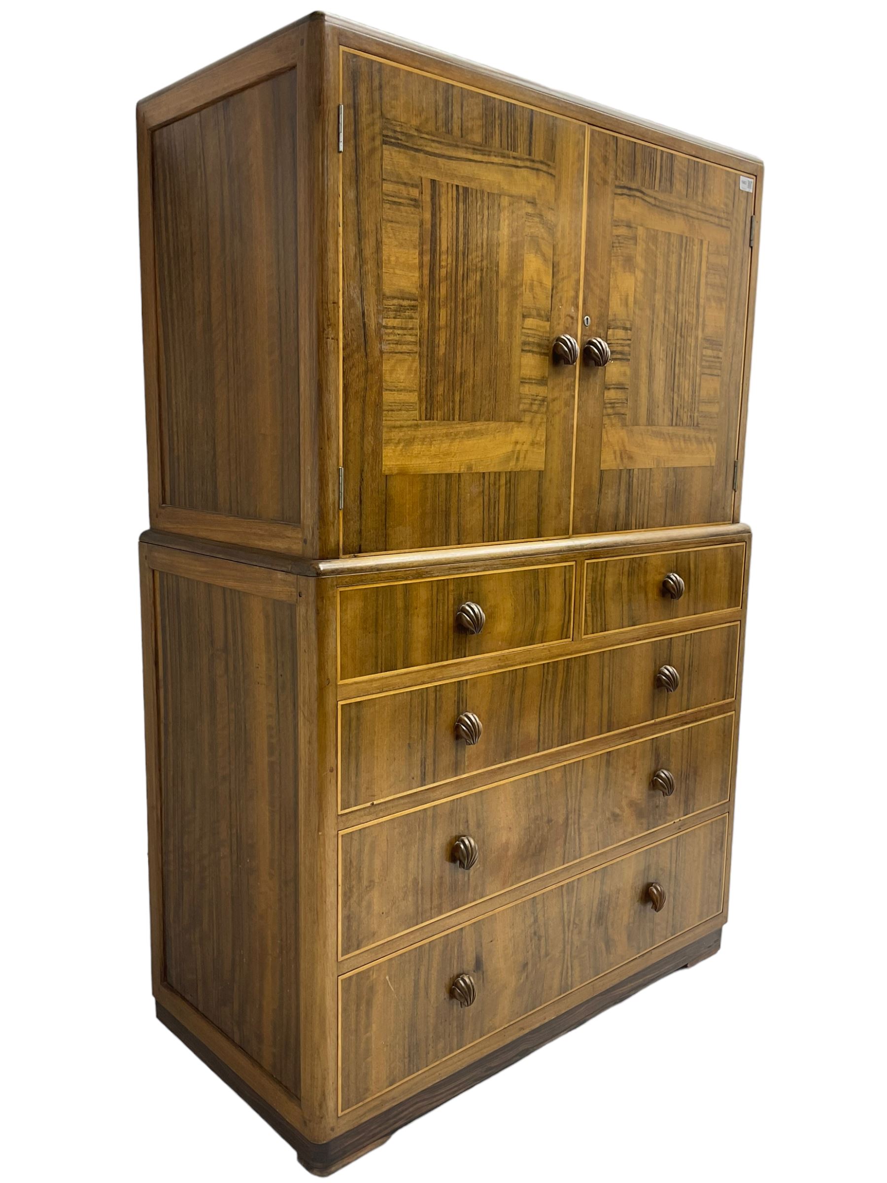 Early 20th century Art Deco walnut cocktail tallboy chest, fitted with double cupboard enclosing two shelves over two short and three long drawers, each with shell shaped handes