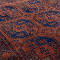 South East Persian Afshar hand-knotted rug, red ground decorated with a geometric design of octagonal medallions and incorporating stylized motifs in tones of indigo and dark brown within geometric borders, with fringe ends  