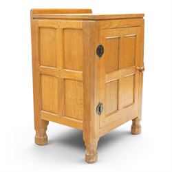 Mouseman - adzed and panelled oak bedside cupboard of small proportions, raised back over rectangular canted top, fitted with single panelled cupboard door with chamfered rails and turned knob handle, enclosing single shelf, raised on octagonal feet,  carved with mouse signature, by the workshop of Robert Thompson of Kilburn