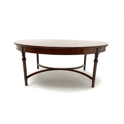 Cross banded mahogany oval coffee table, turned and moulded supports joined by shaped stretcher
