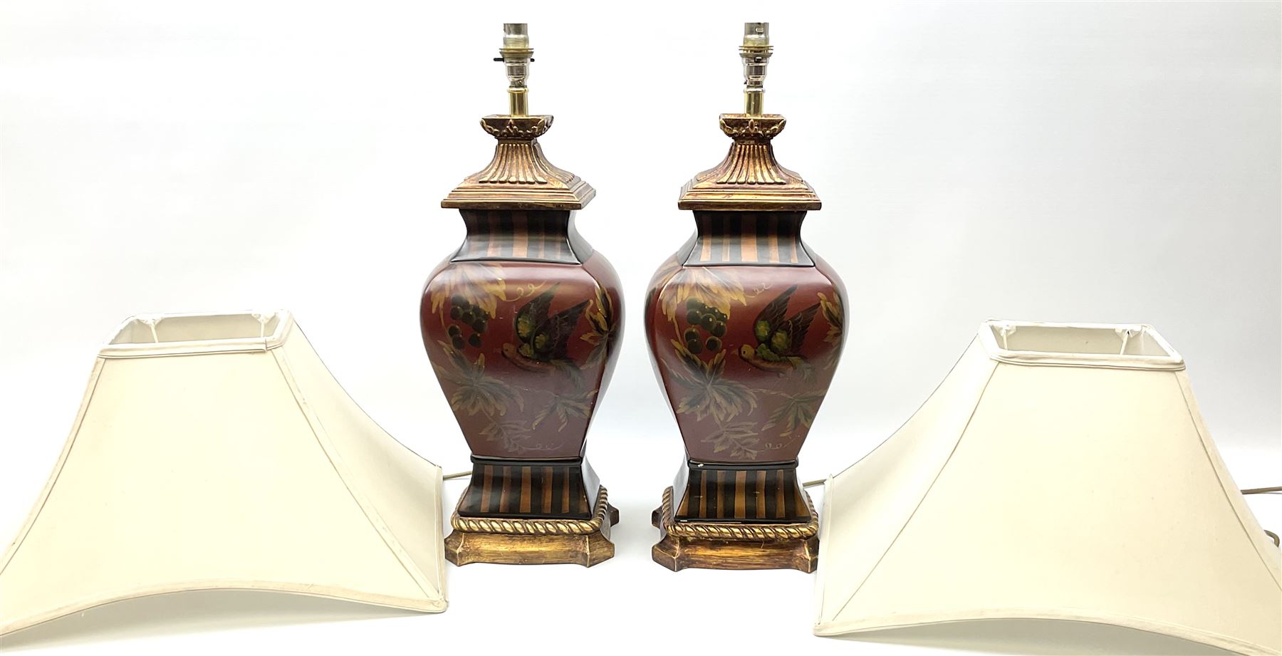 Pair Oriental table lamps decorated with birds in a tree with fruit, on a red ground with a gilded base together with cream lampshades H57cm, without lampshade. 