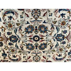 Persian Kashan ivory ground carpet, the field decorated with scrolling branches with foliate and palmette motifs, repeating border with stylised plant motifs, within floral and geometric pattern guard stripes 