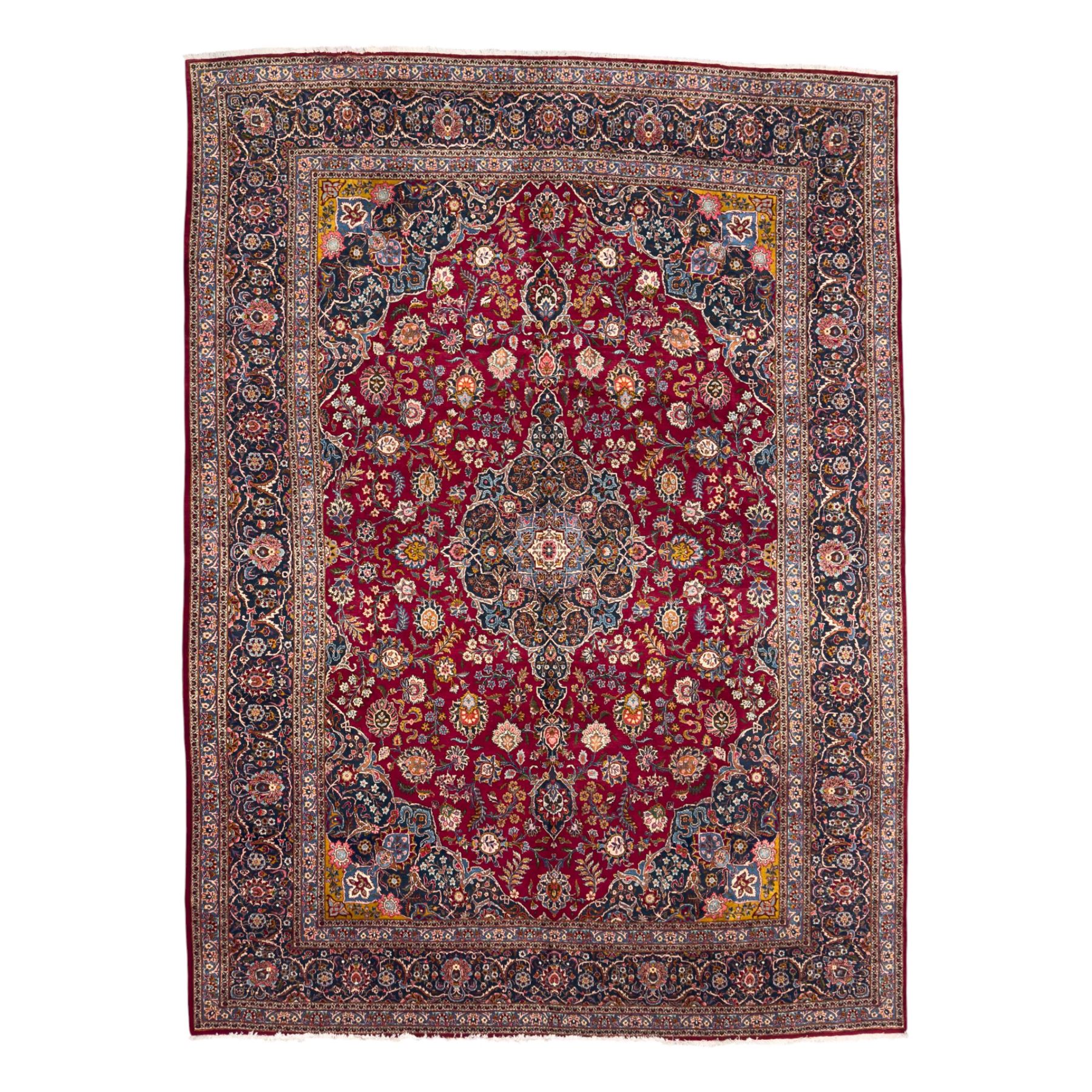Central Persian Kashan hand-knotted carpet, madder red field with an intricate design of scrolling vines, palmettes, and rosettes with a central lobbed medallion with pendant motifs in shades of blue and ivory, and spandrels all within a blue-ground border of palmettes and flowerheads between multiple guard borders, 450cm x 335cm 