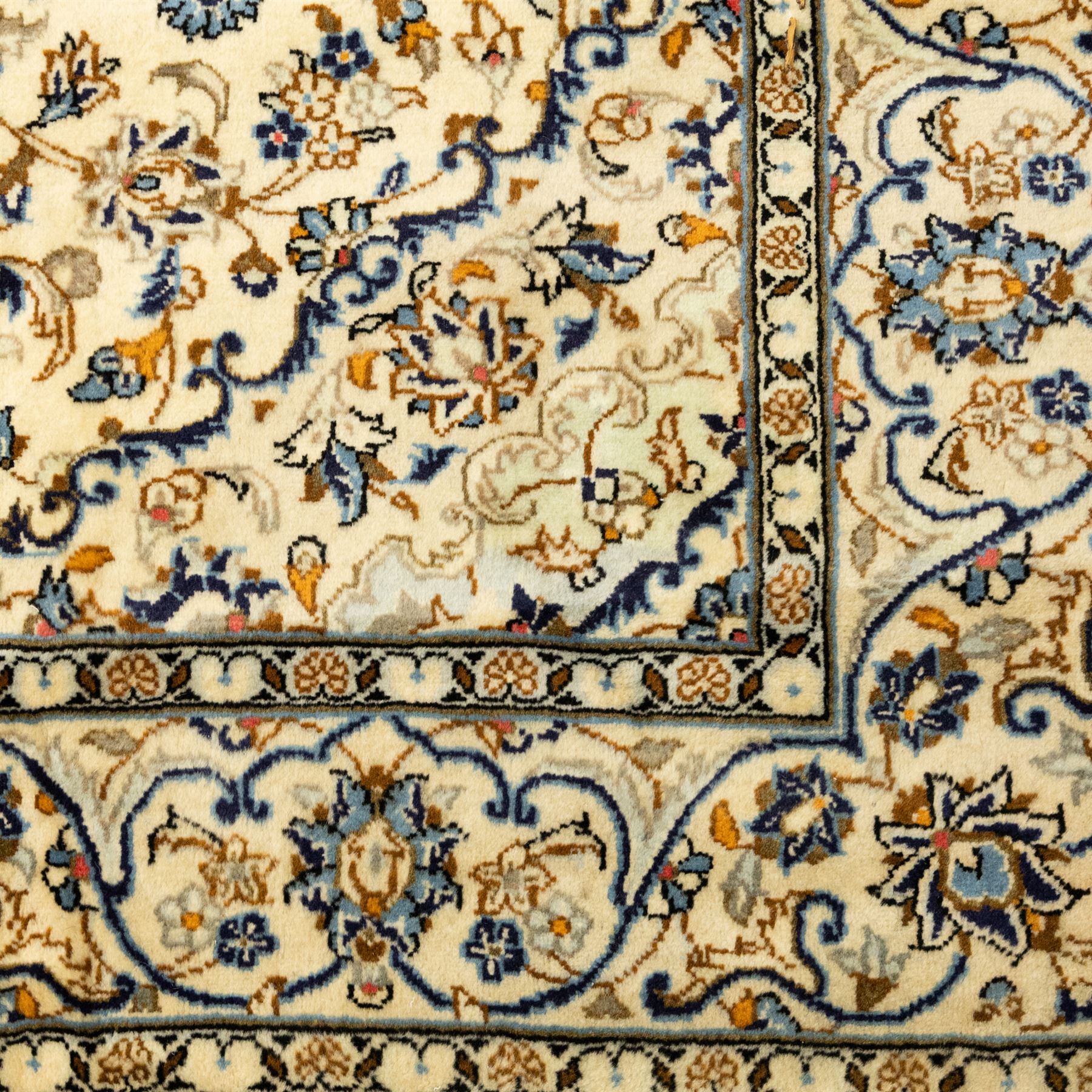 Central Persian Kashan hand-knotted rug, ivory ground, with a small central floral medallion and pendants, the field decorated with fine blue, ochre and beige scrolling vines, flowerheads and palmettes, within an ivory border of repeating floral sprays and meandering vines, flanked by narrow guard stripes, with cotton fringes