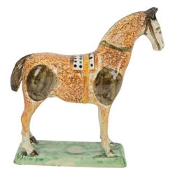 Late 18th/early 19th century Prattware pottery figure of a horse, possibly Yorkshire Potteries, circa 1790-1800, painted and sponge decorated in manganese, with blue spotted saddle secured with a yellow girth, upon a rectangular green base, H15.5cm