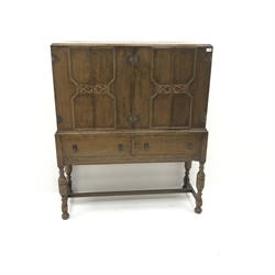 Early 20th century oak cocktail cabinet, four doors enclosing shelves above two drawers, turned supports joined by stretcher, label on back 'Rowntree's, Scarborough - York', W122cm, H145cm, D46cm  