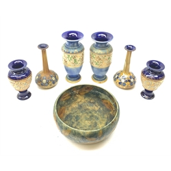 A group of Royal Doulton, comprising a pair of vases of squat bulous form with tall tapering neck, decorated with blue stylised flowers on a brown ground, H18cm, two further pairs of vases, detailed with gilt, and a bowl decorated with leaves upon a merging effect blue ground, D20cm.