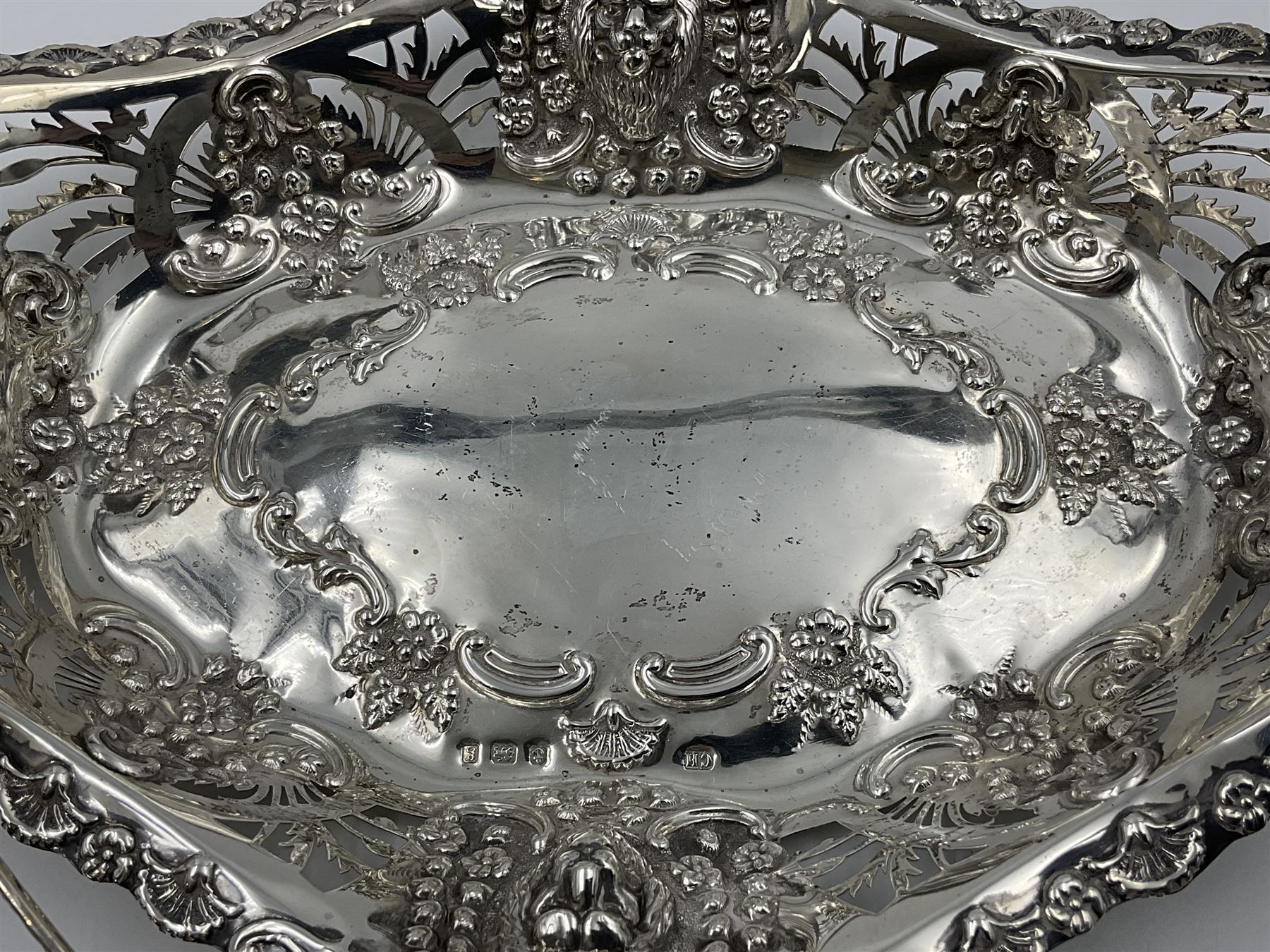 Edwardian silver swing handled basket, of navette form, with four repousse lion masks to each corner and with pierced and embossed floral, scroll and shell decoration to sides, base and handle, hallmarked Charles Horner, Birmingham 1906, height including handle H20cm