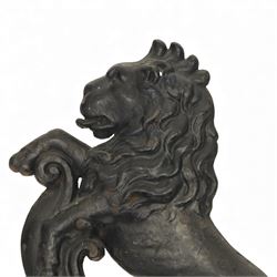 Victorian cast iron figural doorstop in the form of a lion, depicted seated with curled tail and detailed mane, raised foreleg resting against a scroll motif, set on an integral stepped base with moulded edges and foliate ornament