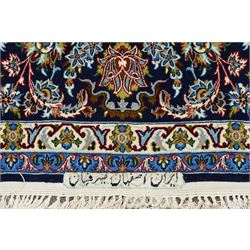 Fine Central Persian Isfahan hand-knotted rug, madder red field with central finely drawn foliate medallion issuing an intricate all-over scrolling vine design with palmettes and arabesques, enclosed by multiple conforming borders in navy ground, signed Isfahan in cartouche, silk fringe ends 