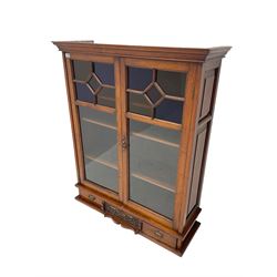 Late Victorian walnut cabinet, moulded cornice over two glazed doors, fitted with three drawers, the centre drawer front carved with foliage and green man mask