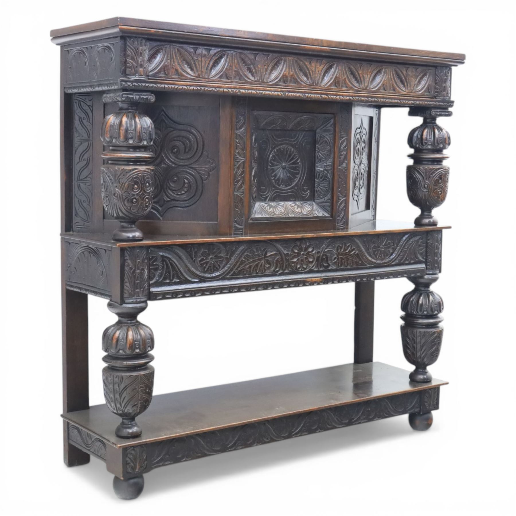 Jacobean revival oak side cabinet, rectangular top above carved frieze of stylised foliage and lunettes, fitted with a central cupboard doors with applied carved panels, above a frieze drawer, supported on turned and carved vase-shaped supports, united by stretcher tier and lower shelf