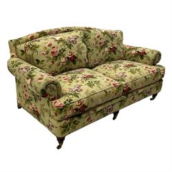 Hancock & Moore - two-seat sofa, upholstered in pale green ground fabric decorated with floral pattern, traditional shape with rolled arms and arched back, on turned front feet with brass cups and castors 