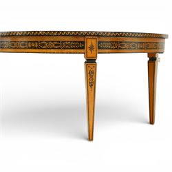 20th-Century Louis XVI-Style satinwood and penwork circular table or pair of console tables, the circular quarter-veneered top decorated in penwork with a central classical mask head motif within scrolling foliate and anthemion ornament on a contrasting black ground, above a conforming frieze decorated with Greek key-type scrolls. Raised on square tapering legs, each with an upper block panel decorated with compass-star motifs.