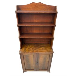 19th century mahogany bookcase on cupboard, raised three tier waterfall bookcase on cupboard enclosed by two panelled doors, on bracket feet
