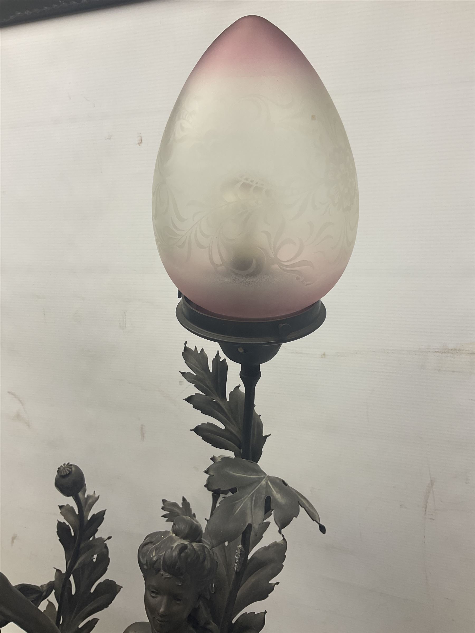 Pair of Art Nouveau style spelter figural table lamps, each mounted on rouge marble effect circular bases, with toleware flower heads and leafy decoration surrounding a female figure, H90cm